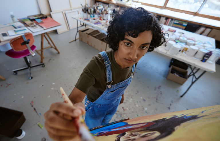 Top view of a woman painting on a canvas.